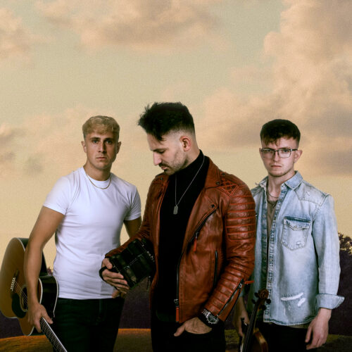 Three male musicians stood looking seriously, holding their instruments - a guitar, accordion and a violin.